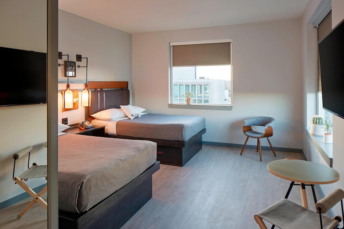 Een moderne hotelkamer met twee bedden, een televisie, een raam met uitzicht en een klein tafeltje.