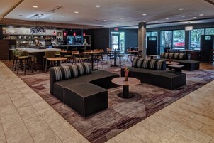 A modern lounge area with seating, a bar, and large windows.