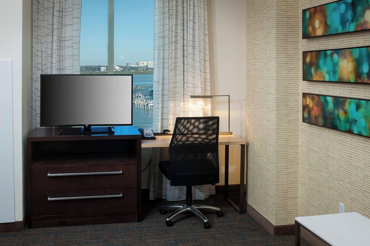 Une chambre d’hôtel équipée d’un bureau, d’une télévision et d’œuvres d’art accrochées au mur.