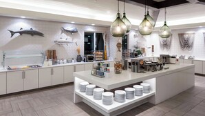 Une cuisine moderne dotée d’un îlot central, de meubles blancs et d’une variété d’aliments et d’ustensiles de cuisine.