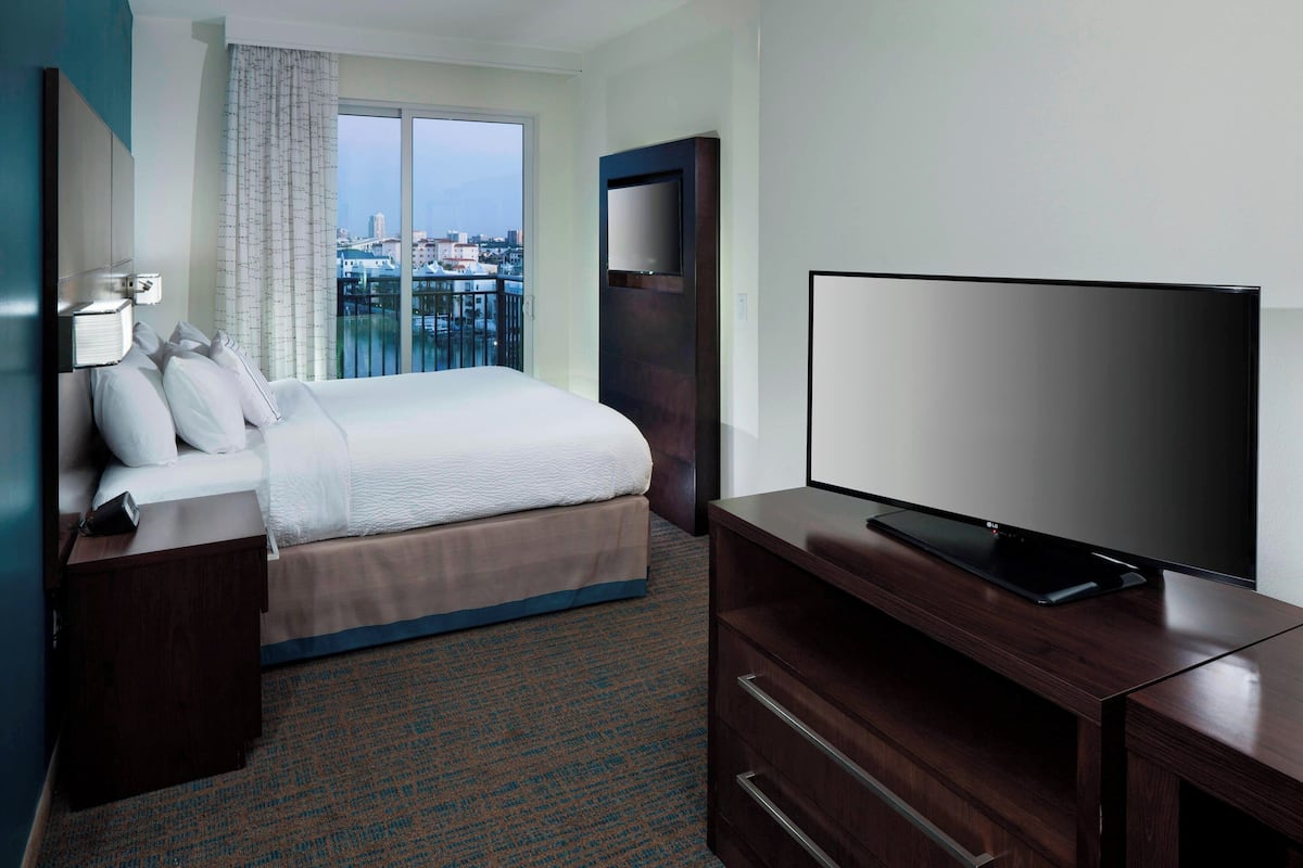 Une chambre d’hôtel avec un lit, une télévision, une table de chevet et une vue sur la ville par la fenêtre.