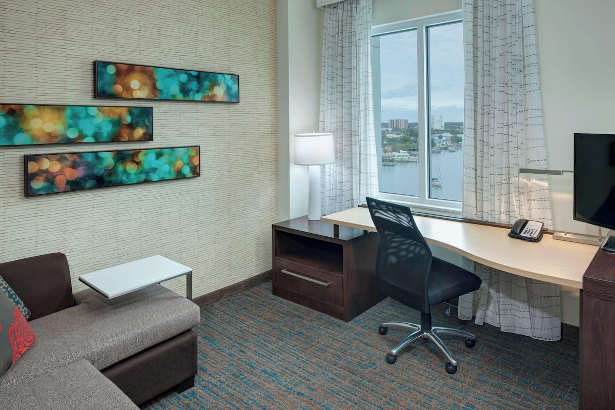Une chambre d’hôtel équipée d’un bureau, d’une chaise, d’un canapé et d’œuvres d’art accrochées au mur.