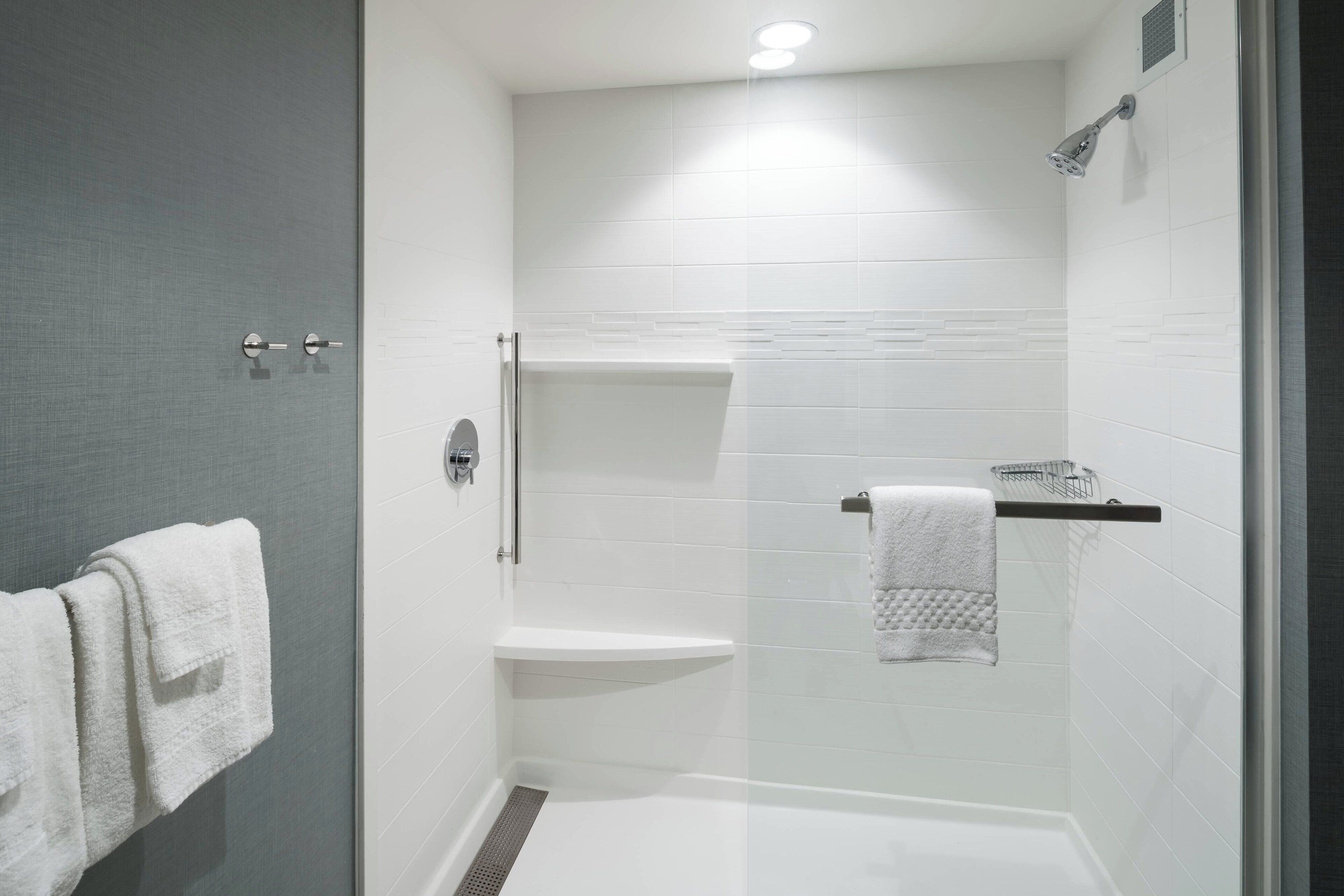 Ein modernes Badezimmer mit Duschkabine aus Glas, einer weißen Toilette und einem Handtuchhalter mit zwei Handtüchern.