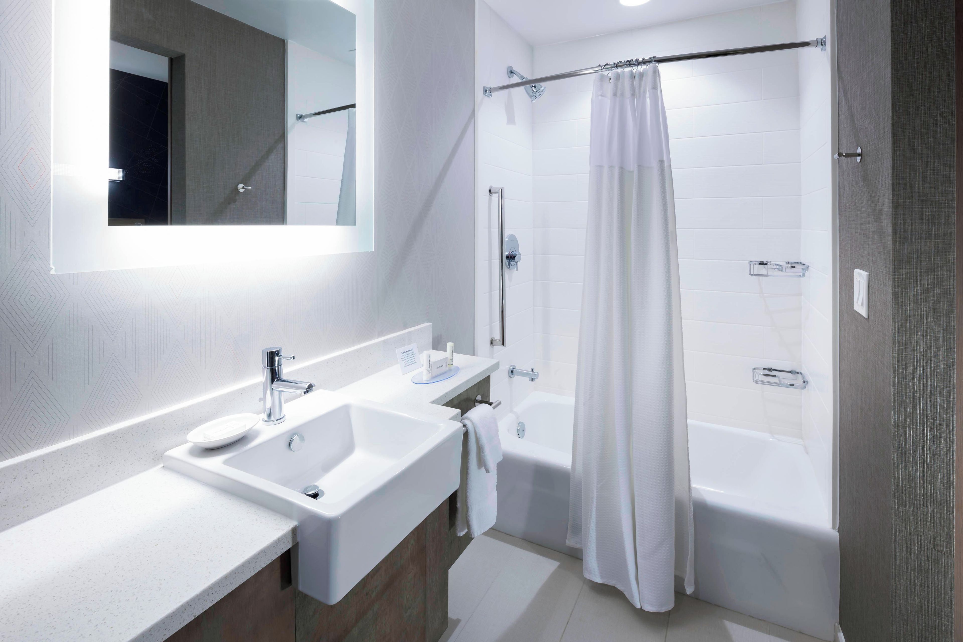 A modern bathroom with a double sink, a bathtub, and a shower curtain.