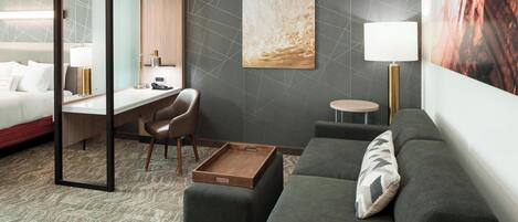 Una habitación de hotel moderna con una cama, un escritorio, una silla, un sofá y una mesita.