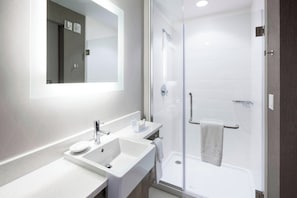 A modern bathroom with a white sink, mirror, and glass shower enclosure. - SpringHill Suites by Marriott Clearwater Beach (Clearwater Beach)