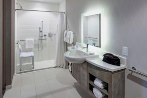 Bathroom features a glass-enclosed shower, sink, and vanity with a towel rack.