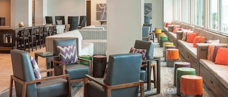 A modern lobby with seating areas, a bar, and large windows.