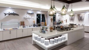 Una cocina moderna con una isla central, armarios blancos y un mural con motivos marinos.