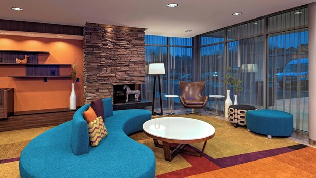Eine moderne Lobby mit einer Wand aus Stein, einem blauen Sofa, einem runden Couchtisch und einem Kamin.