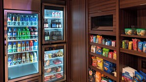 Ein Selbstbedienungskühlschrank mit verschiedenen Getränken und ein Verkaufsregal mit Snacks.