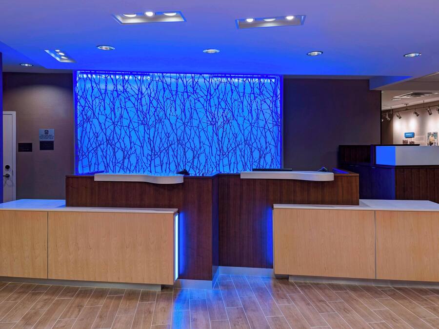 A reception area with a modern design, featuring a wooden reception desk and a blue illuminated wall.