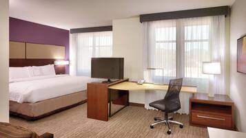 A hotel room with a bed, a desk with a computer, a chair, and a TV.