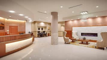 Eine moderne Hotelhalle mit Rezeption, Sitzgelegenheiten und Kamin.