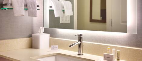 A modern bathroom with a large mirror, a sink with a chrome faucet, and two towels hanging on a towel rack.