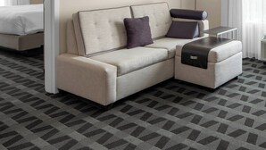 A hotel room with a sofa, a small table, a lamp, and a bed. - TownePlace Suites by Marriott Charlotte Fort Mill (Fort Mill)