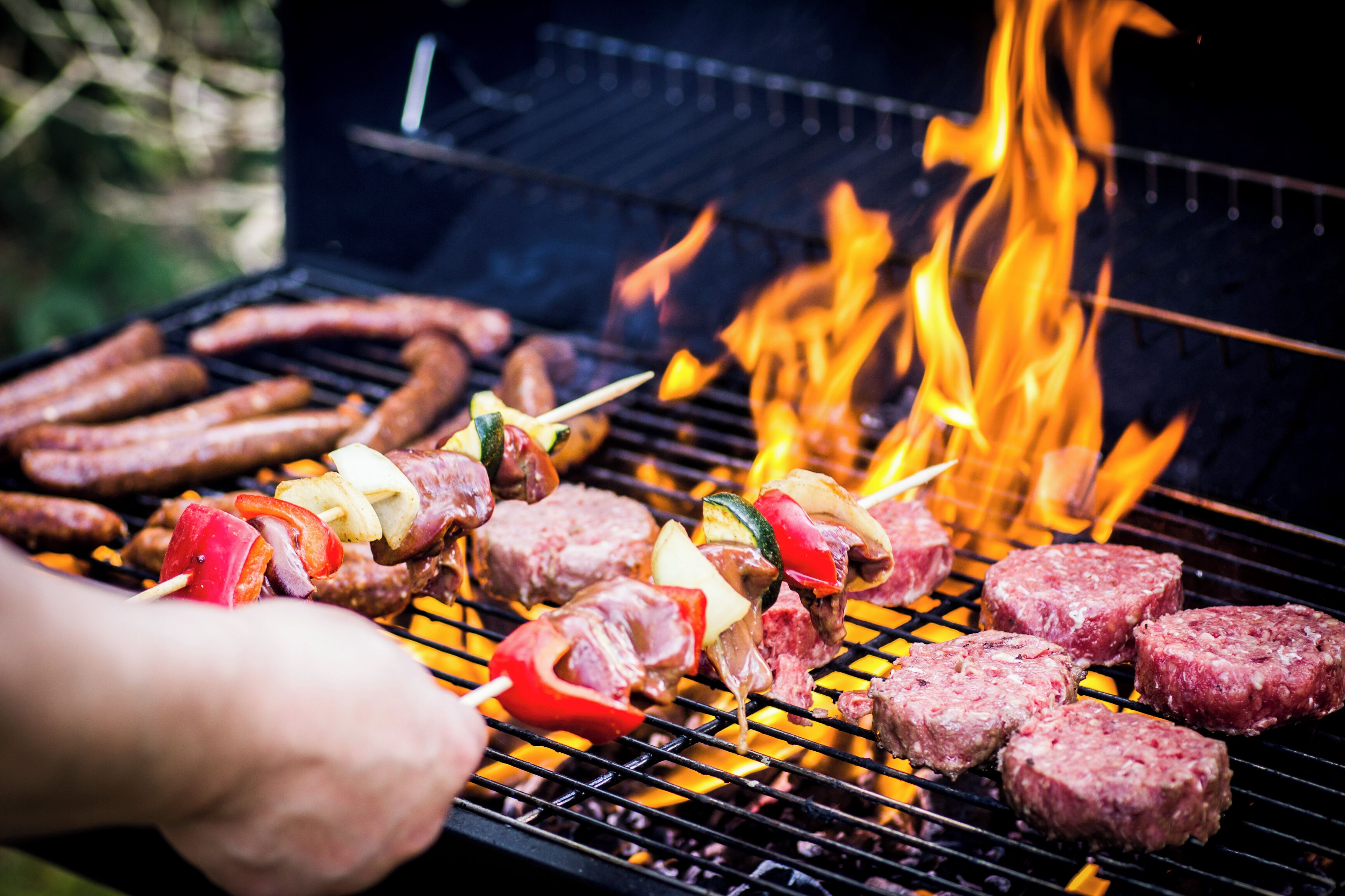 A grill with various meats and vegetables being cooked over an open flame.