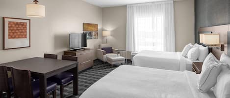 Een hotelkamer met een groot bed, een bureau met stoel, een televisie en een raam met gordijnen.