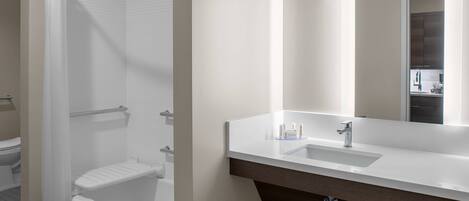 A modern bathroom with a bathtub, a sink, and a large mirror.
