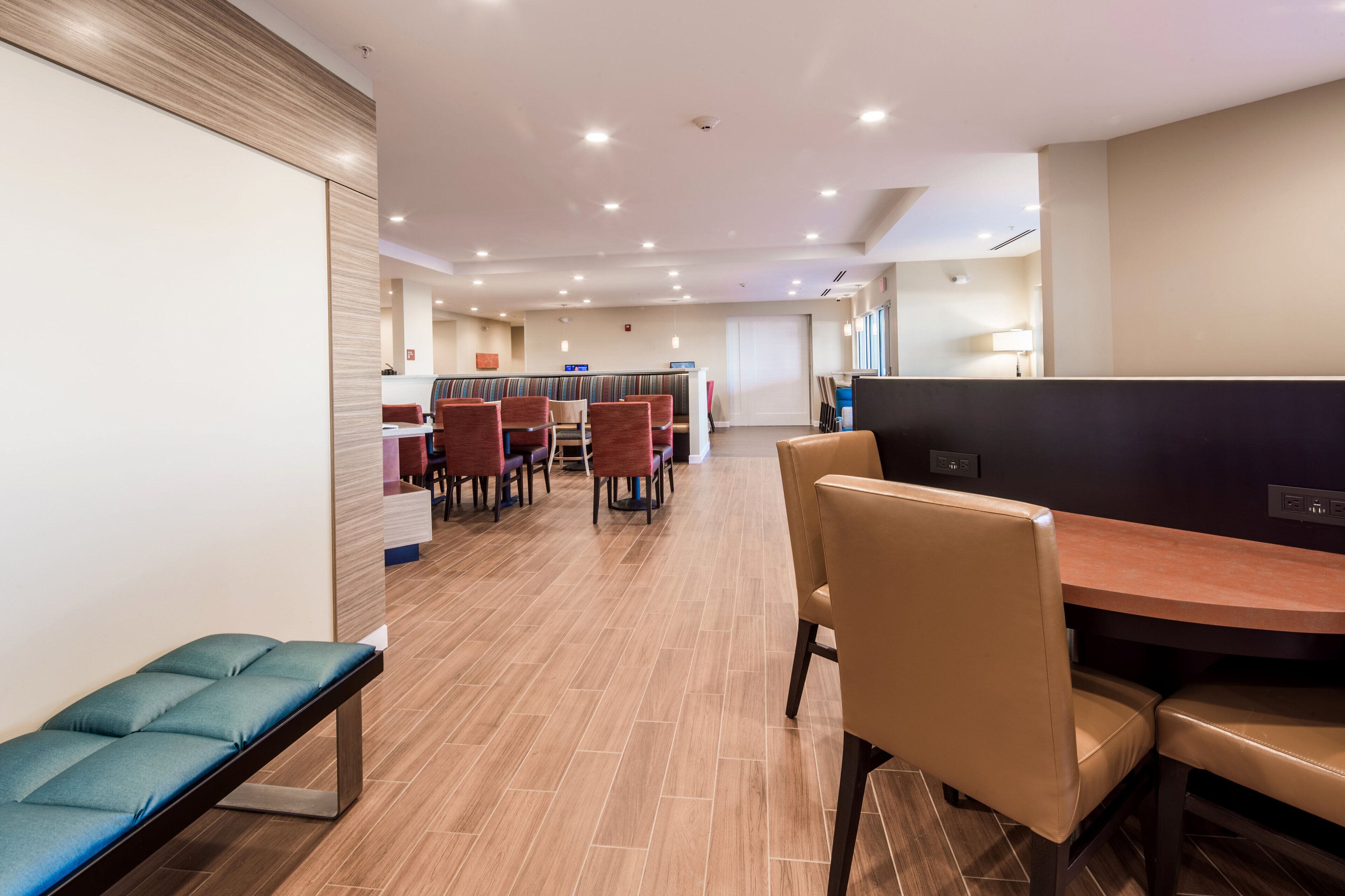 Una hall moderna di un hotel con una reception, un'area salotto e una panca.