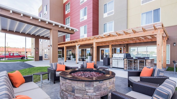An outdoor seating area with a stone fire pit, wicker furniture, and a covered patio. - TownePlace Suites by Marriott Cleveland (Cleveland)