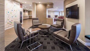 A modern lounge area with sofas, a coffee table, and a map on the wall. - TownePlace Suites by Marriott Cleveland (Cleveland)