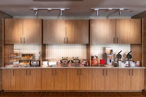 Una cocina moderna con armarios de madera, salpicadero de azulejos y varios electrodomésticos como tostadora, máquina para gofres y cafetera.