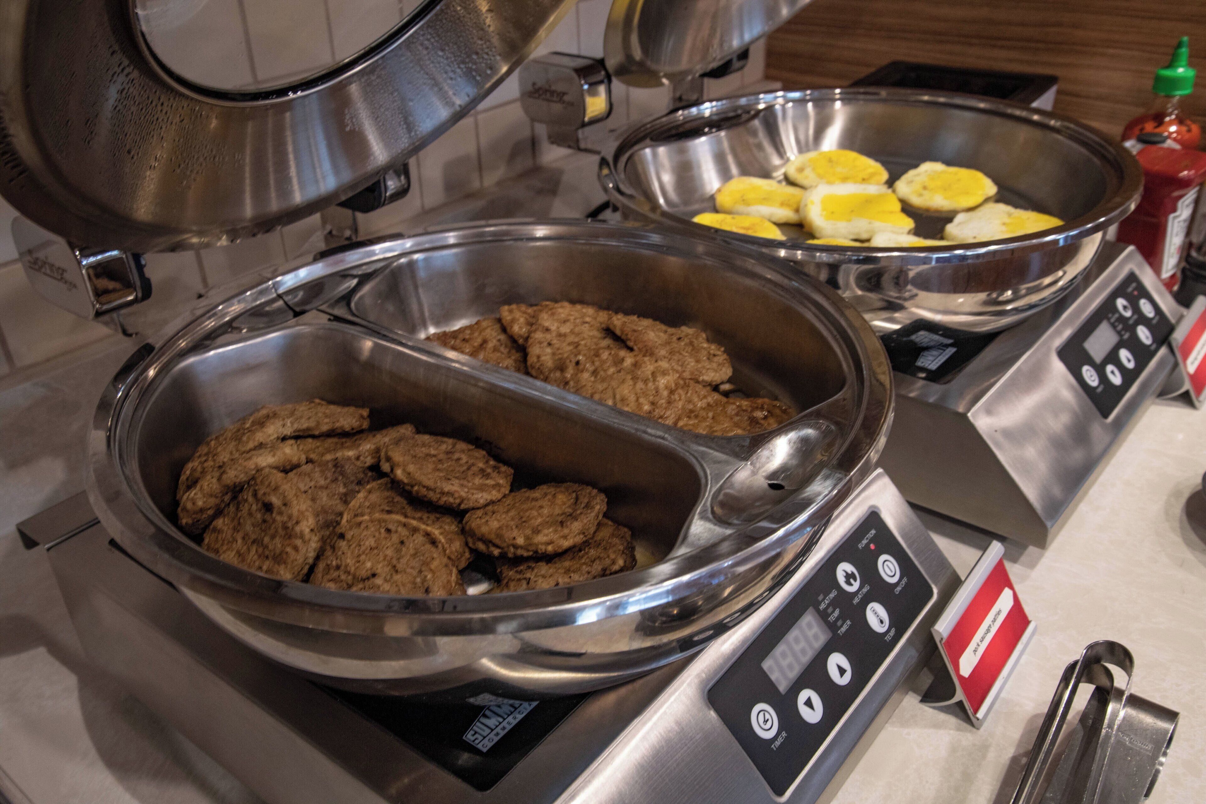 Un buffet composé de deux grands récipients en métal remplis de différents aliments, d’une balance et d’assaisonnements.