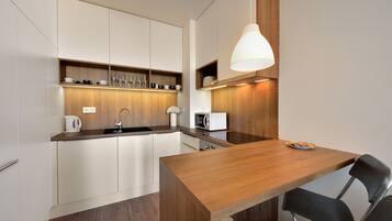 Een moderne keuken met witte kasten, een houten aanrecht, een spoelbak, een magnetron en een eettafel met stoelen.