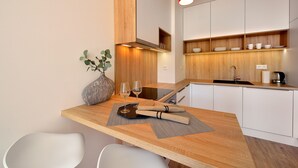 A modern kitchen with wooden cabinetry, a built-in oven, and a countertop with a vase and two glasses. - Apollis Business & Budget by Ambiente (Bratislava)