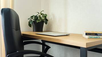 A modern office chair, a wooden desk, a laptop, a potted plant, and a book titled "Tiny Habits" by Sally Rooney.