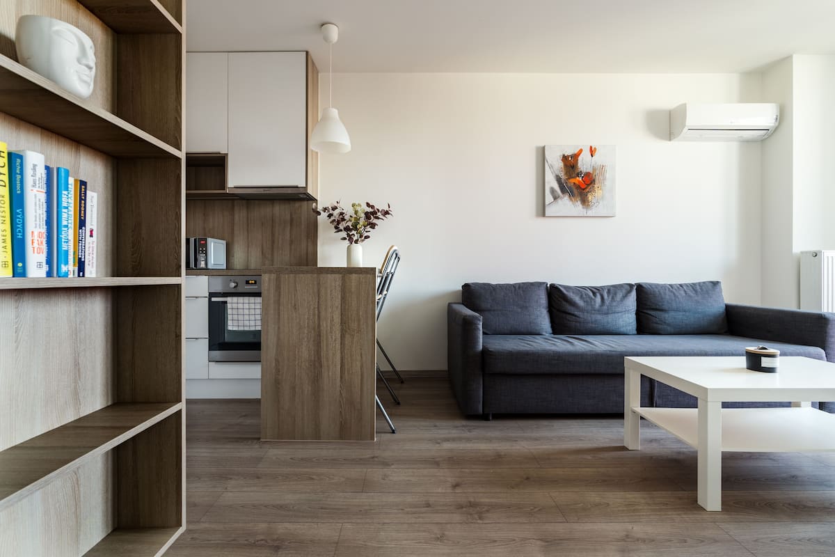A modern living room with a grey sofa, a white coffee table, and a bookshelf with books.