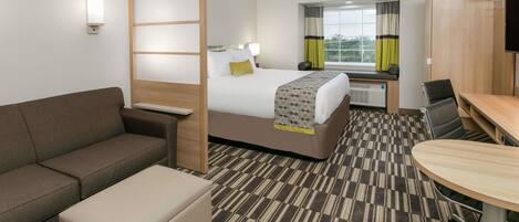 A hotel room with a bed, a sofa, a small table, and a TV.