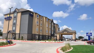 Un hotel Microtel con diseño moderno, que cuenta con un amplio toldo de entrada y estacionamiento.