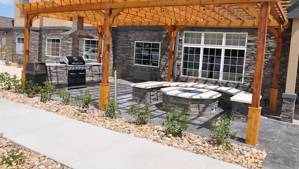 A covered patio with a grill, stone seating, and a stone wall. - Microtel Inn & Suites by Wyndham Lubbock (Lubbock)