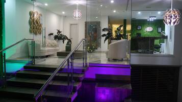 A modern interior with a staircase, a sofa, and a reception desk.