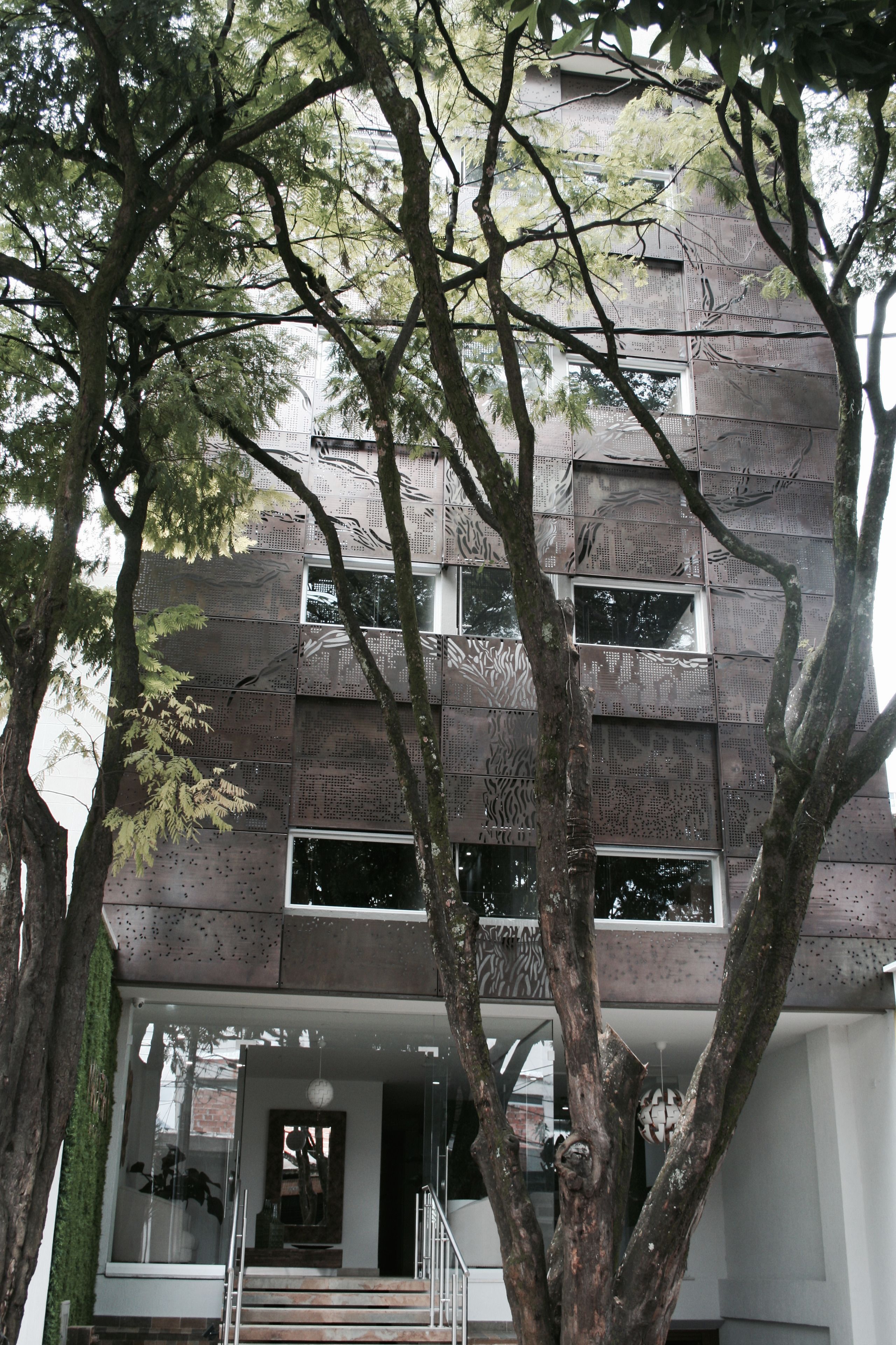 A modern building with a flat roof, large windows, and a staircase leading to the entrance.