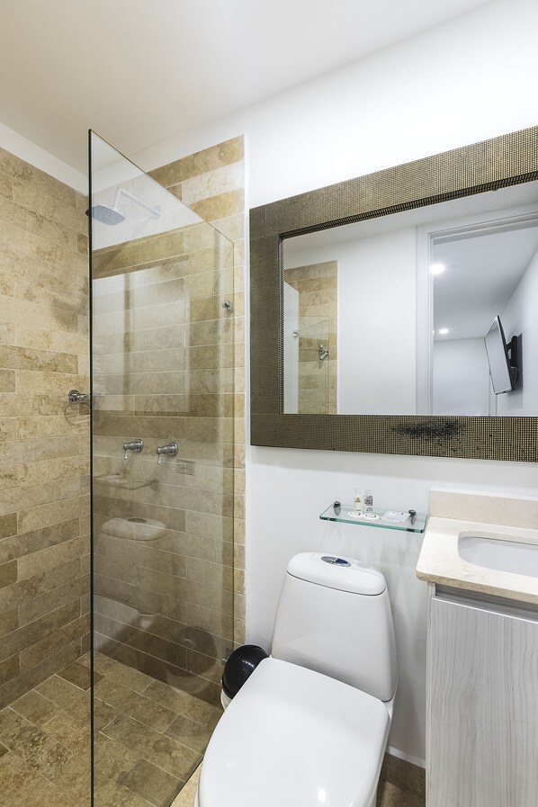 A modern bathroom with a glass-enclosed shower, a white toilet, and a large mirror above the sink.