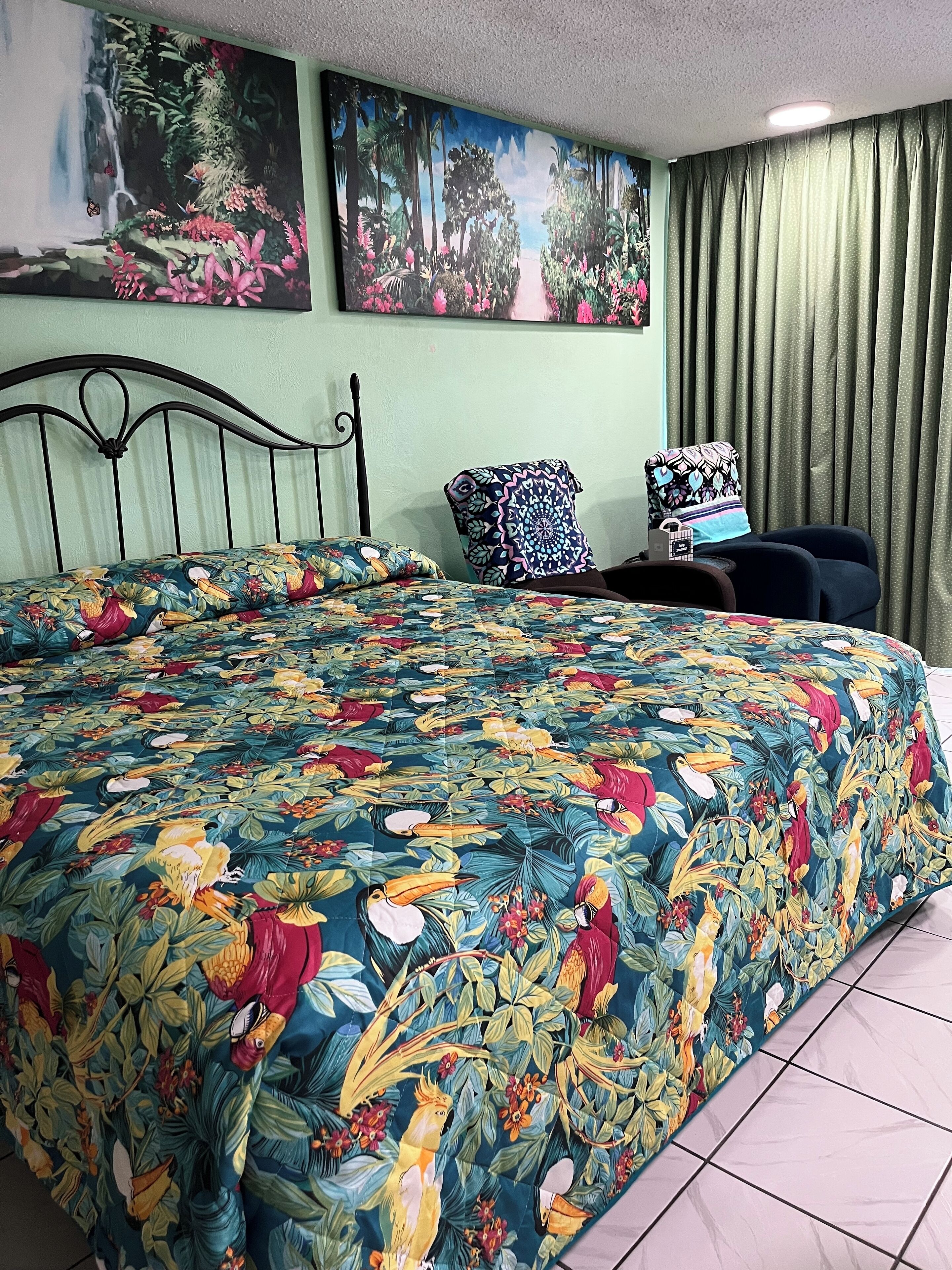Un dormitorio con cama, mesita de noche, silla y dos cuadros en la pared.
