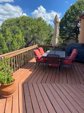 Une terrasse en bois avec une table et des chaises, entourée d’une balustrade en bois.