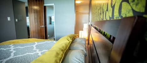 Ein Hotelzimmer mit einem Bett, einem hölzernen Kopfteil, einem Nachttisch und einer Wand mit strukturierter Oberfläche.