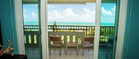 Ein Balkon mit Blick auf das Meer, einem Tisch und zwei Stühlen.