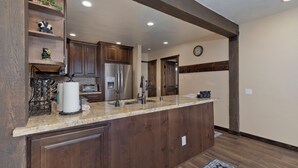A kitchen with wooden cabinets, a stainless steel refrigerator, a sink, and a countertop with a paper towel holder. - Mammoth Condo, 2 Beds+ 2 Baths, Next To Canyon Lodge-Mammoth Ski & Racquet Club (Mammoth Lakes)