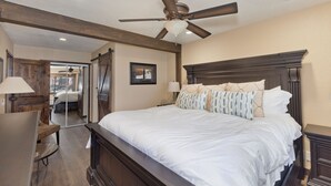 A bedroom with a large bed, wooden headboard, ceiling fan, bedside lamps, and a desk with a chair. - Mammoth Condo, 2 Beds+ 2 Baths, Next To Canyon Lodge-Mammoth Ski & Racquet Club (Mammoth Lakes)