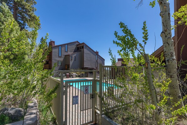 A residential building with a swimming pool, surrounded by trees and a gated entrance. - Mammoth Condo, 2 Beds+ 2 Baths, Next To Canyon Lodge-Mammoth Ski & Racquet Club (Mammoth Lakes)