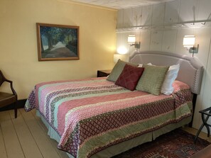 A bedroom with a bed, a painting on the wall, and two wall-mounted lamps. - The Tannery! Private Dipping Pool In The Warm Springs Stream! Pet Friendly! (Warm Springs)