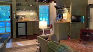 A cozy kitchen with wooden beams, a dining area with a sofa, and a television. - The Tannery!  Private Dipping Pool In The Warm Springs Stream!  Pet Friendly!  (Warm Springs)