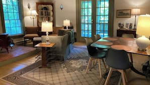 A dining area with a wooden table, chairs, and a patterned rug. There are two lamps on the table and a bookshelf in the background. - The Tannery!  Private Dipping Pool In The Warm Springs Stream!  Pet Friendly!  (Warm Springs)