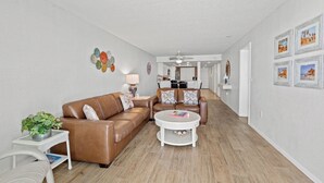 Ein Wohnzimmer mit einem braunen Ledersofa, einem weißen Couchtisch und einem kleinen Beistelltisch mit einer Pflanze.