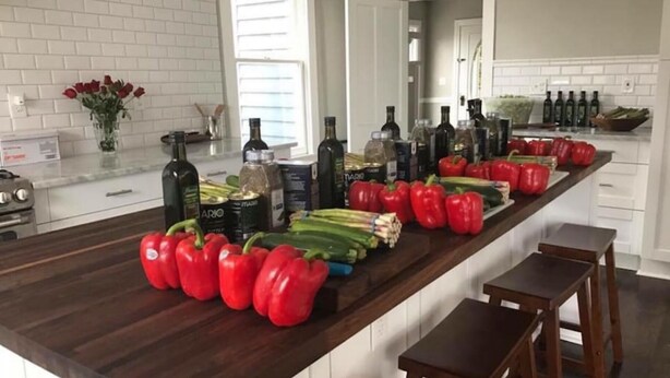A kitchen counter with red bell peppers, green onions, and various bottles of olive oil. - Serene Sauna Retreat with Chefs Kitchen, Luxury Beds & Luxury Baths (West Point)